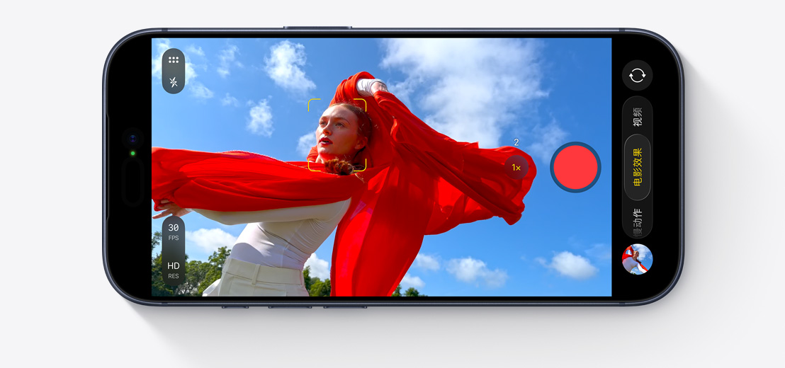 iPhone 屏幕展示使用电影效果模式拍摄人物在户外跳舞的画面，人物身上的红色围巾轻舞飞扬。