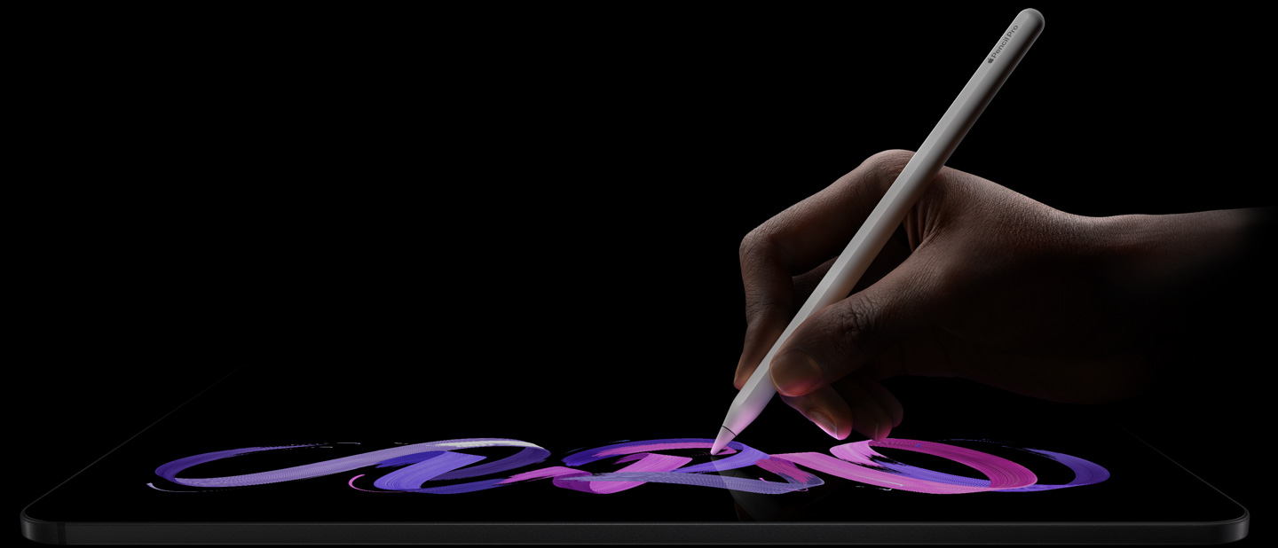 深空黑色 iPad Pro 横屏放置，正面外观展示侧面机身；一只手握着白色 Apple Pencil Pro 在屏幕上绘制紫色和粉色的抽象图案。