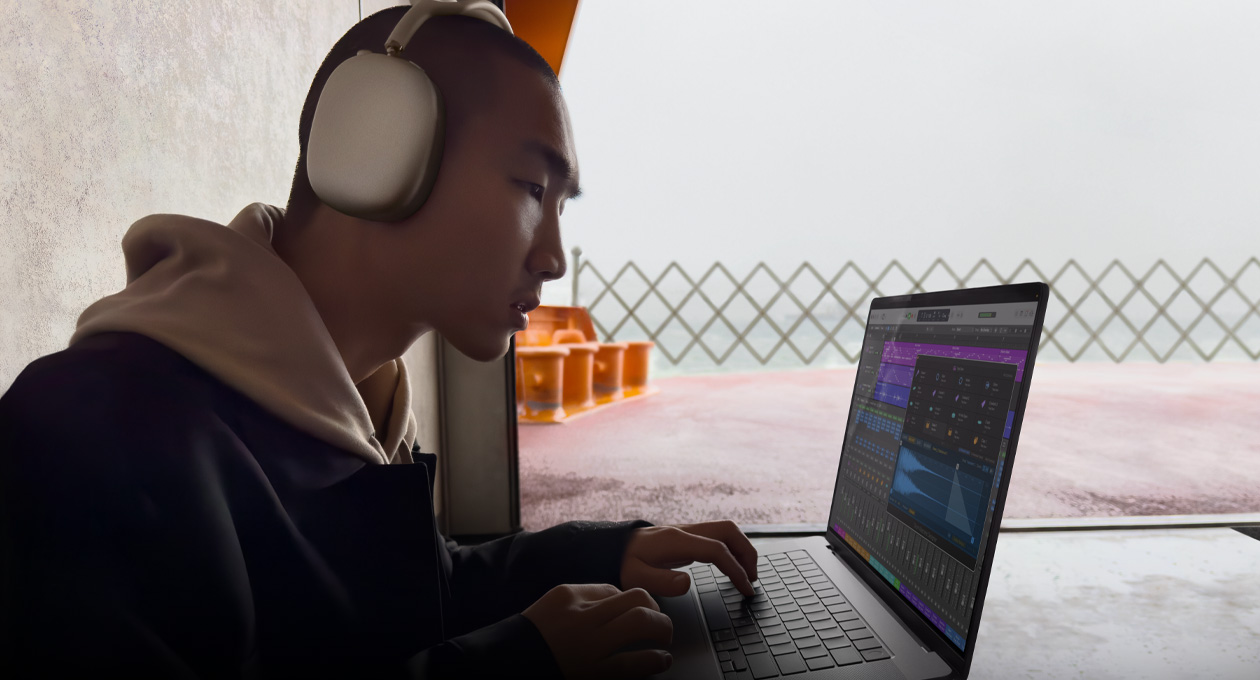 一个人头戴 AirPods Max 的侧面图，他正在 16 英寸 MacBook Pro 上使用 Logic Pro。