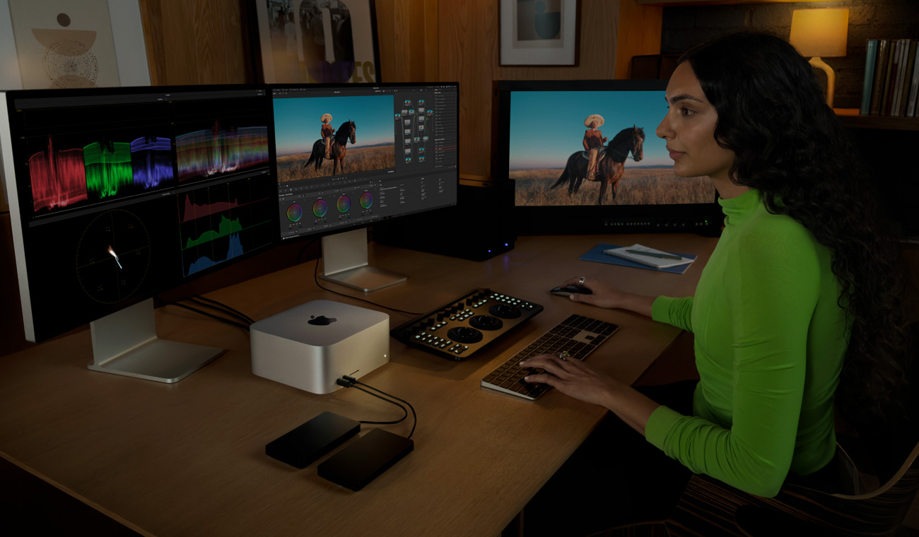 一位专业人士使用 Mac Studio 编辑文件，电脑外接有三台显示器