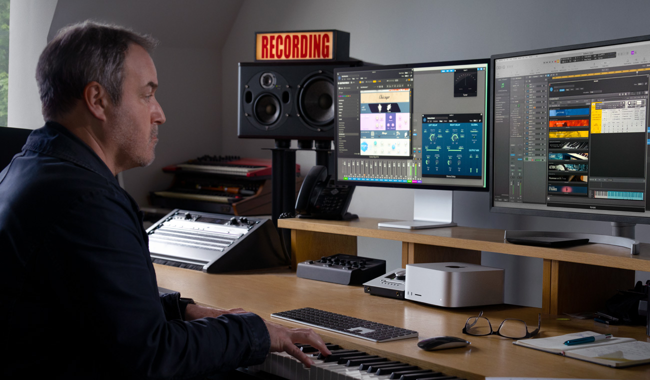 一位音乐人用钢琴在配有 Studio Display 的 Mac Studio 上创作音频混音