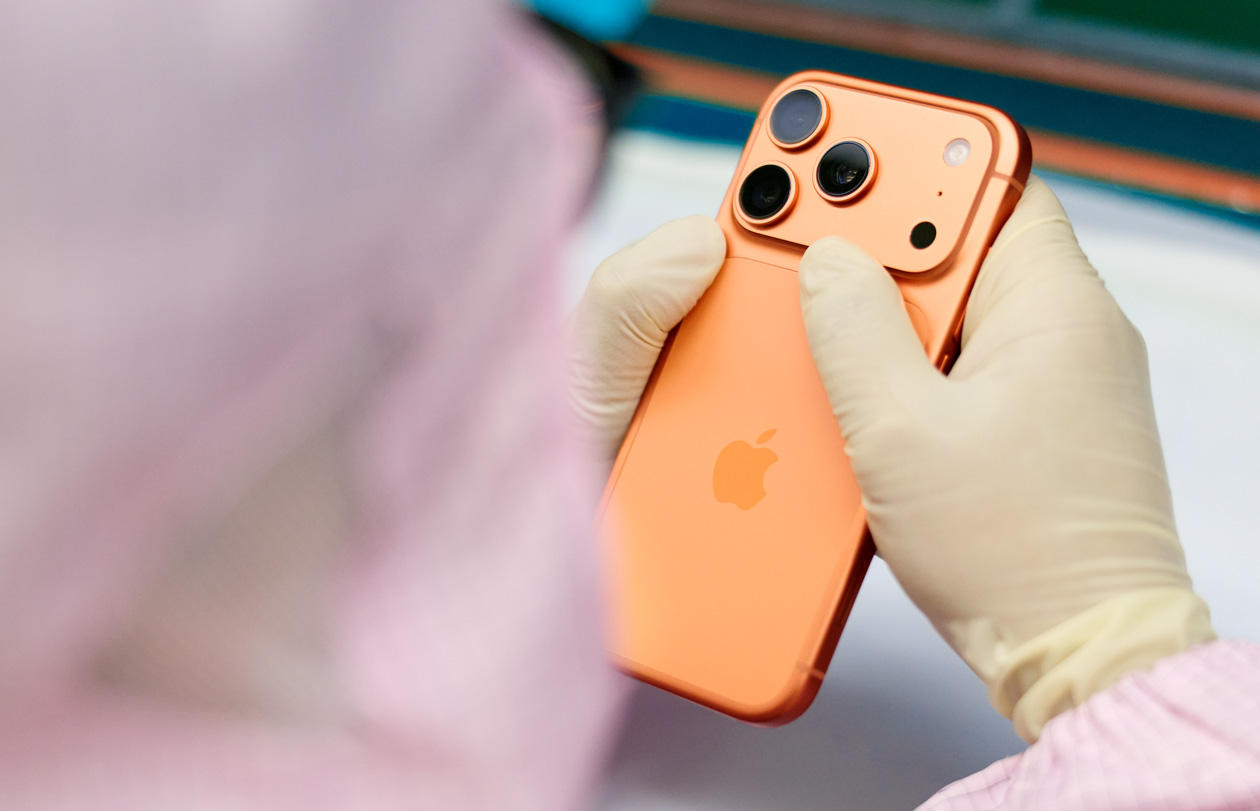 一名身着连体工作服的员工在工作台前检查 iPhone